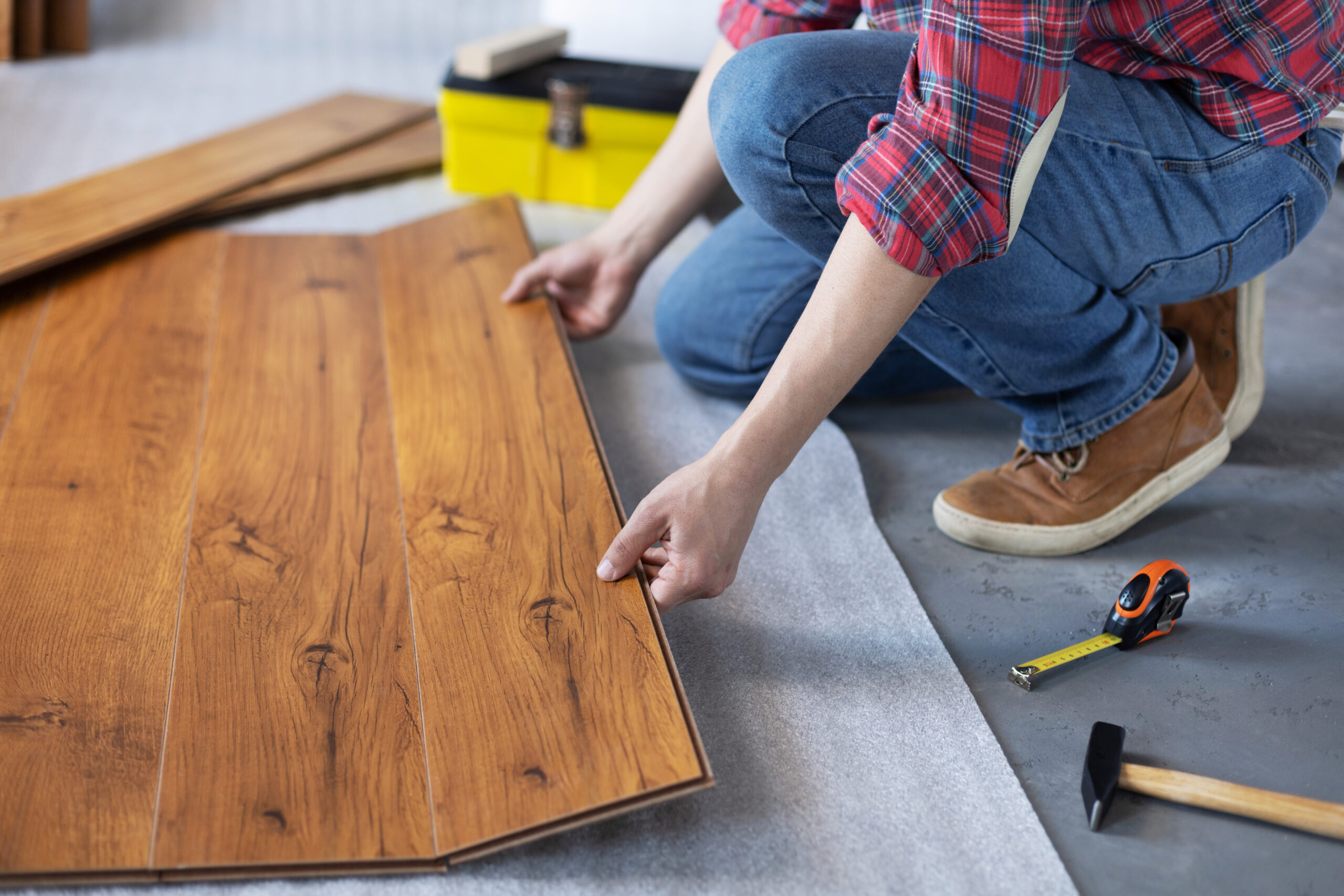 Man worker installing laminate flooring. Wooden laminate floor plank and tools